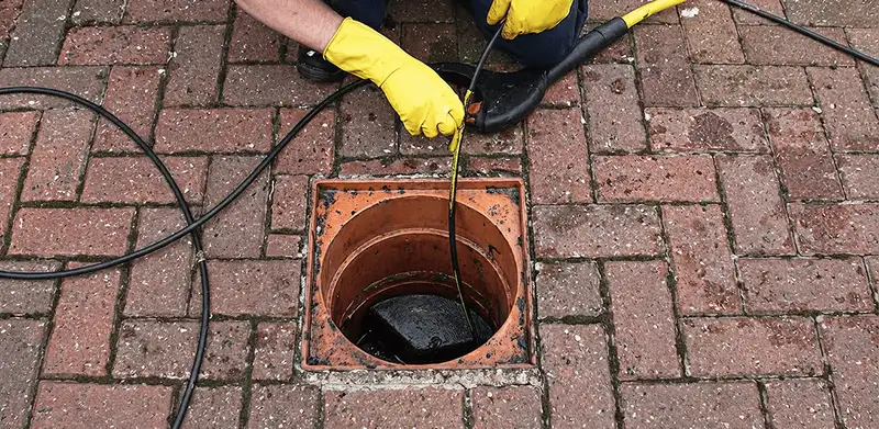 Drain cleaning technician using a drain snake to clear a clogged drain in Naperville, IL