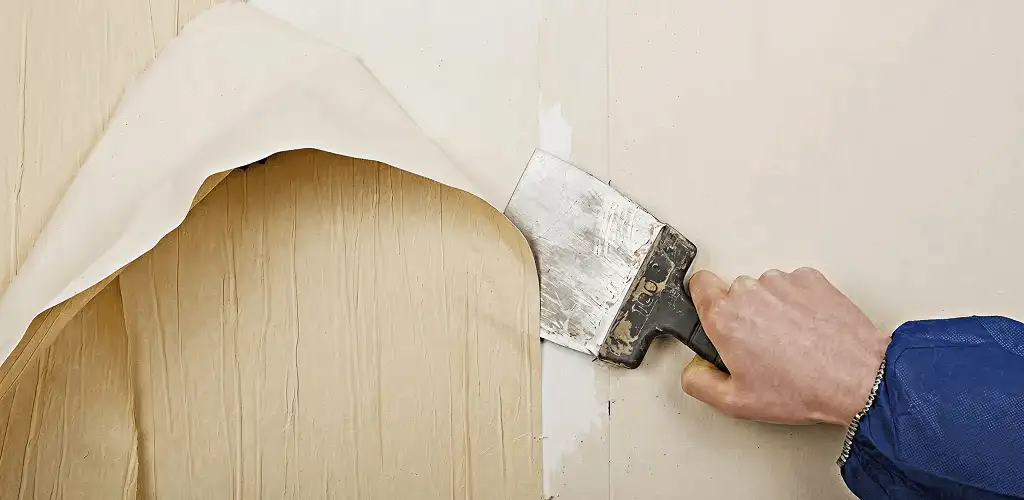 Handyman removing wallpaper with a scraper for wall preparation in Naperville, IL