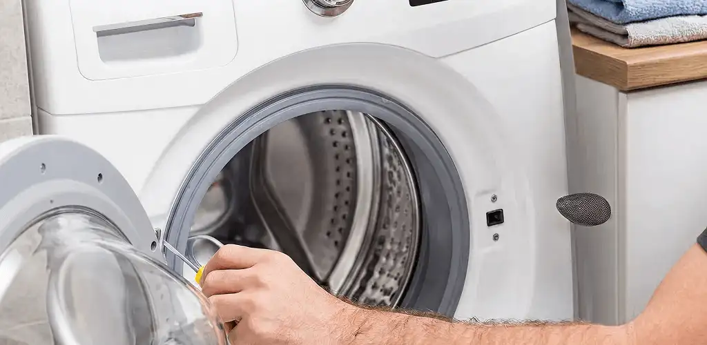 Handyman repairing a front-load washing machine and inspecting the drum in Naperville, IL