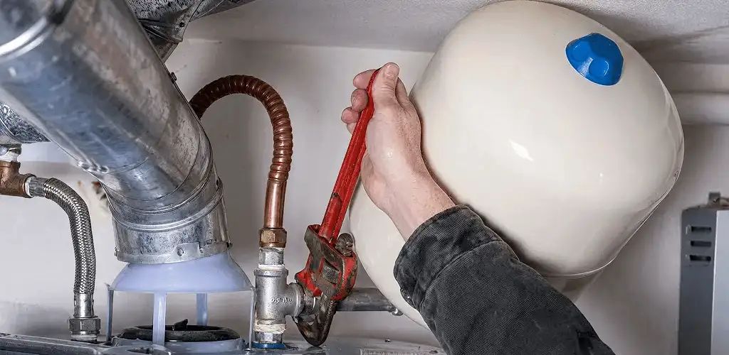 Water heater repair technician tightening plumbing connections near a tank unit in Naperville, IL