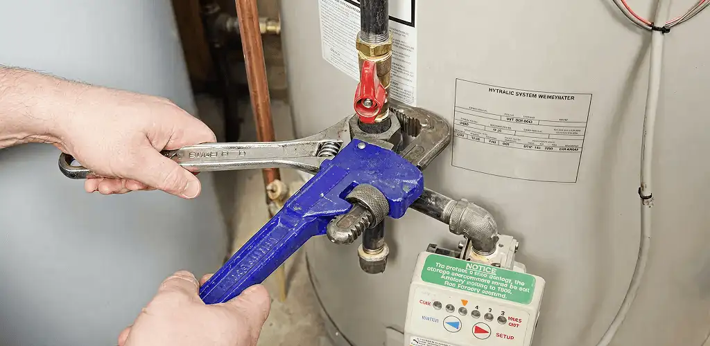 Water heater repair technician tightening the shutoff valve and supply line in Naperville, IL